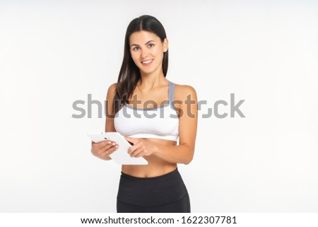 athlete girl on a white background is watching a sports application in a tablet