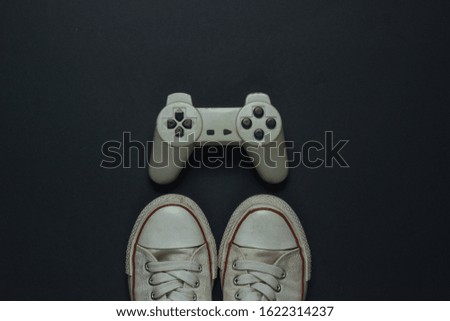 Retro old sneakers and gamepad on black background. 80s. Top view