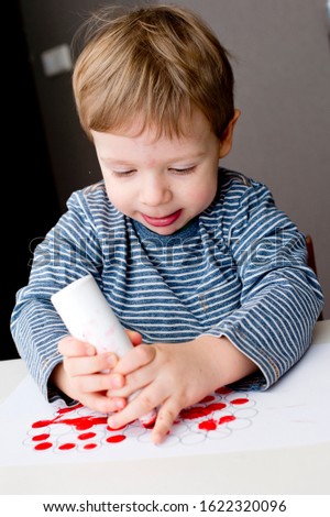 fine motor skills, hand coordination. little toddler making stamps on paper with heart shape print. St. Valentine's theme.