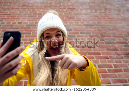 Attractive blonde woman using a smartphone on a brick wall
