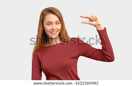 Pretty girl shows gesture little bit. Size concept. Beautiful young woman wears Burgundy-colored jacket sleeves isolated on white background in Studio with an empty space for text and advertising.