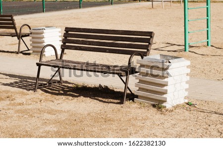 a tree bench on a sports ground on a sunny day