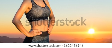 A young trained slender girl stands opposite a beautiful sunset in the mountains.