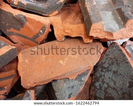 Broken clay roof tiles lie on a pile