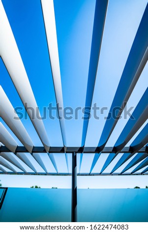 Modern metal beams stretching across space outdoors on a sunny day with blue sky.