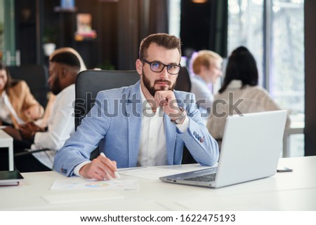 Close up handsome confident bearded office manager in business suit works with laptop at the office room.