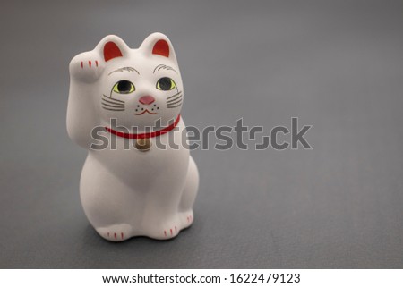 Close up of Japanese lucky cat charm Maneki Neko isolated in grey background