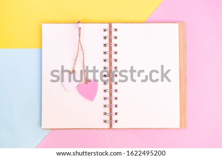 Open otebook with pink and white wooden hearts on them. Send message to your lover on Valentine's day.