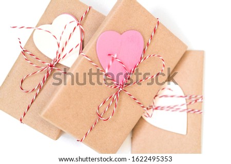 Gift boxes wrapped in craft paper and decorated with red ribbon and wooden hearts on white background. Valentines day, wedding or other holiday decorations background