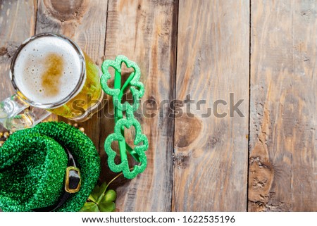 St. Patricks Day green shamrocks with a full cold glass of beer background