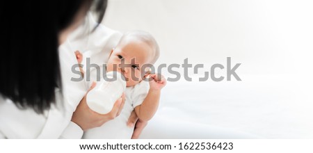 Mother feeding asian baby with bottle of milk, banner copy space Royalty-Free Stock Photo #1622536423