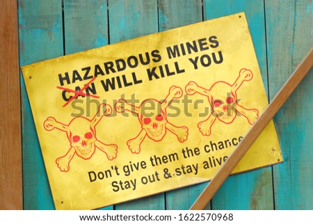 "hazardous mines can will kill you" warning board on a wooden wall