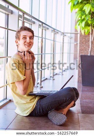 Carefree teenage boy using wi-fi internet connect in commerce center 