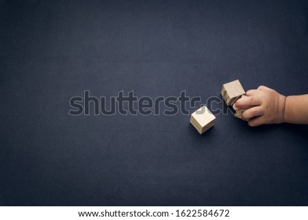 Wooden cube alphabet closeup and children hands on black background. Selective focus and education concept