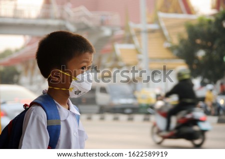 Asian student boy wearing dust mask 
 and air pollution with pm 2.5 at Bangkok, Thailand Royalty-Free Stock Photo #1622589919