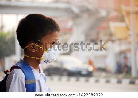 Asian student boy wearing dust mask 
 and air pollution with pm 2.5 at Bangkok, Thailand Royalty-Free Stock Photo #1622589922