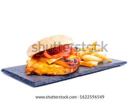 A picture of cheesy bbq grilled burger with fries insight on slate plate.