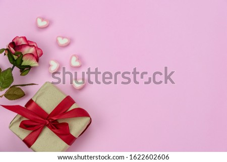 Table top view image of decoration valentine's day background concept.Flat lay red rose and essential symbol love season with gift box on modern rustic pink paper at home office desk studio.