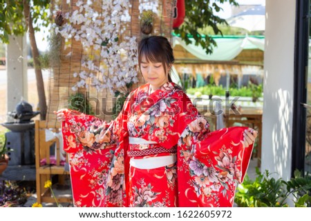 The girl is wearing a red traditional kimono, which is the national dress of Japan
