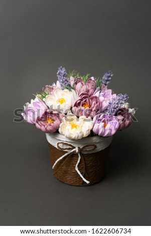 Flowers in bloom: Bouquet of lilac and pink wild flowers in a straw basket on a gray background.