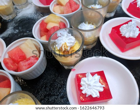 Top view of sweet red strawberry jelly topped with whip cream, chocolate mousse, strawberry yoghurts and mixed fruit in cup as a background in restaurant, summer dessert