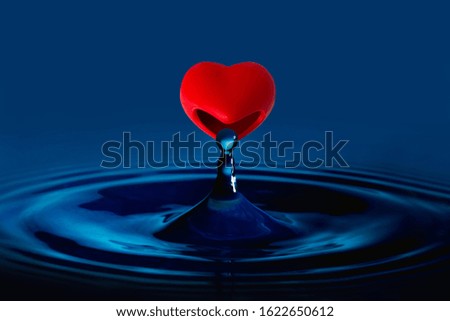 The red heart is eating water drop splash in a glass cup blue colored.Valentines concept
