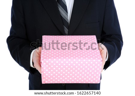 Valentine's Day. A handsome man in a suit holds a pink and white spotted gift box. Valentines Day gift in a mans hands. Isolated on white. Room for text. clipping path. Valentines Day February 14th.

