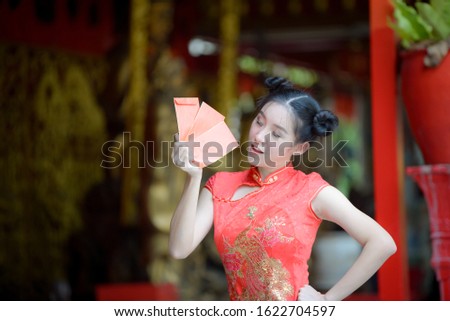 Asian beautiful woman girl in the Cheongsam red dress up open the red envelope with money, in the Chinese New Year. Festivities, New Year Celebration
