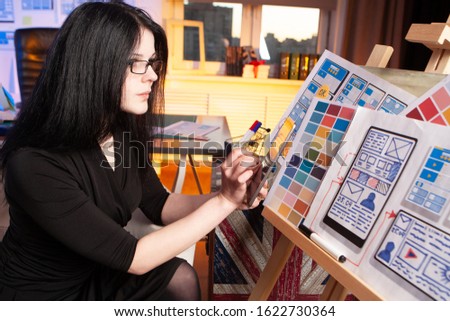 UX design. Woman chooses a color scheme for a mobile application. Business woman chooses color of mobile site. Web designer at work. Woman works as a designer. Color palette on the girl?s stand.