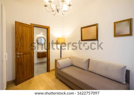 Modern cozy interior of small living room. Grey couch. Opened door.