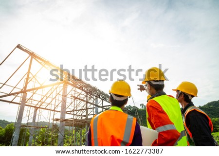 Engineer technician watching team of  worker control in Construction workers wearing safety clothing and discussing on construction site checking office laptop at construction site.