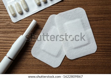 Nicotine patches, pills and electronic cigarette on wooden table, flat lay Royalty-Free Stock Photo #1622809867