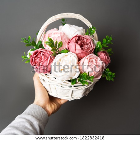 Flowers in bloom: A bouquet of lilac and white peonies in a brown bascket in a male hand.