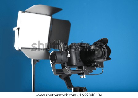 Professional video camera and lighting equipment on blue background