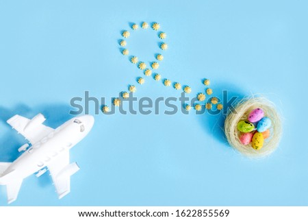plane flies on blue background.yellow sweets. Direction sign for easter eggs. Spring and Easter are coming.Beautiful creative arrow made of colored eggs. Pointer or cursor from eggs. Top view flat