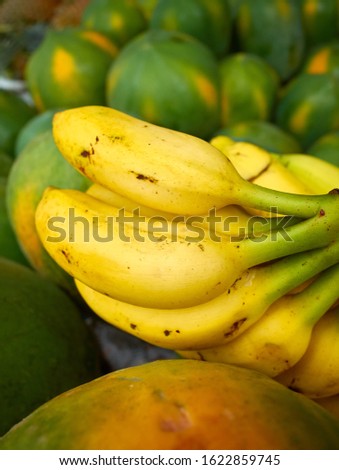 Close up picture of ripe bananas among papayas on a local market, selective focus.