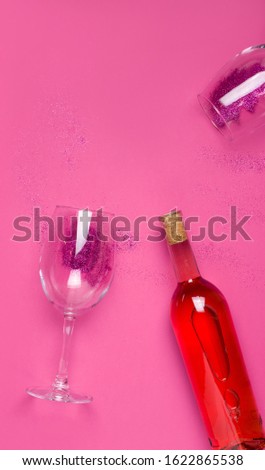 Vertical image with copy space, a bottle of wine and two glasses with sparkles on a pink background. The concept of holidays, Women's Day, Valentine's Day, Christmas, birthday