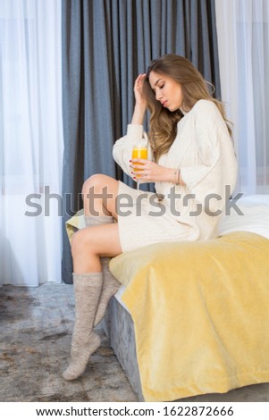 Beautiful young woman drinking orange juice in the bed