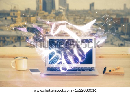 Desktop computer background in office and handshake hologram drawing. Double exposure. Pertnership concept.