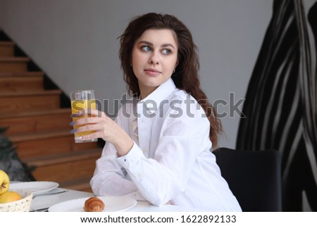 woman has breakfast at home with orange juice and croissant, lifestyle photo