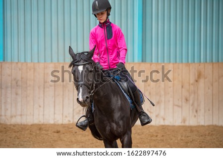 Young Girl riding horse at school. equitation. Riding young woman on horse in manege. Beautiful smiling young woman close-up with horse. Horse and jockey Royalty-Free Stock Photo #1622897476