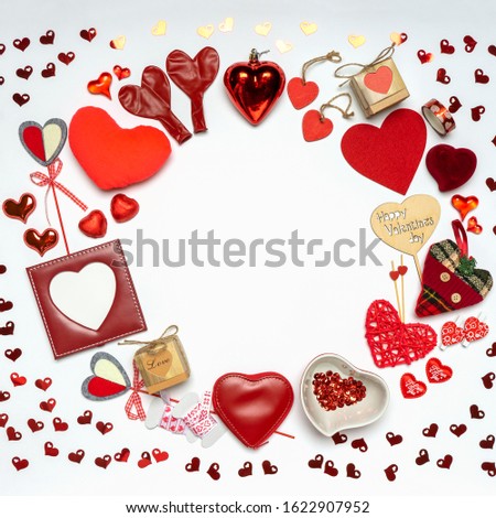 Round frame made of various decorative red hearts and romantic items: gifts, sweets, photoframe on white background. Love, romance or Valentine's day concept. Greeting card with space for text