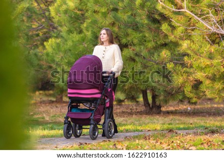 Mom walks with newborn baby in autumn city park
