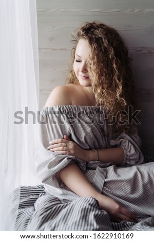 curly blonde in retro dress with bare shoulders romantically covered her eyes