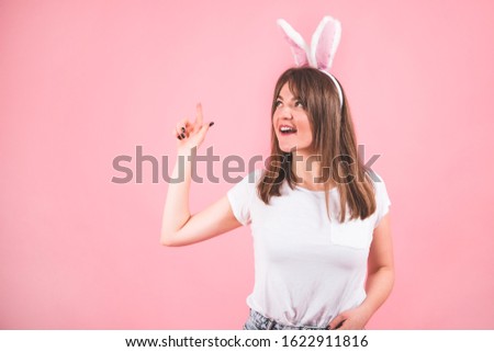 Happy Easter. Portrait of a pretty lovely girl wearing bunny ears standing isolated over pink background. Emotions. Easter concept
