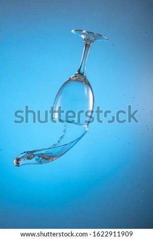 wine glass falling with a big splash of a stream of wine on a blue background