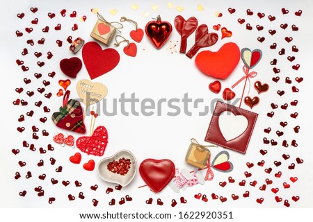 Round frame made of various decorative red hearts and romantic items: gifts, sweets, photoframe on white background. Love, romance or Valentine's day concept. Greeting card with space for text