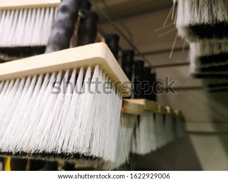 a brush with a plastic handle and a wooden base for repair is sold in a large building materials store in the paint materials department.