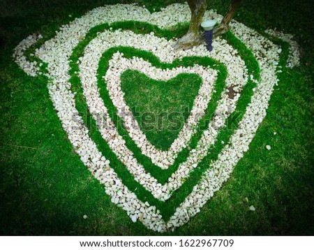 Top view  of heart shape white stones on the grass for landscape design. Backdrop for Valentine’s day or romantic background for wedding post card or marketing advertisment