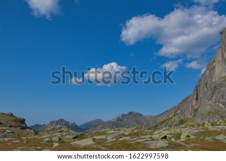 peak under blue sky with clouds, preparation for climbing rock ridge, journey in mountain valley